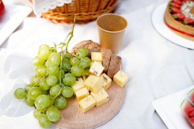 Piknik peyniri, ekmek, pasta ve üzüm beyaz masada. rustik arkaplan