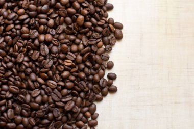 Koyu kahve taneleri açık ahşap masanın üzerinde duruyor, arka plan görüntüsü. metin için yer