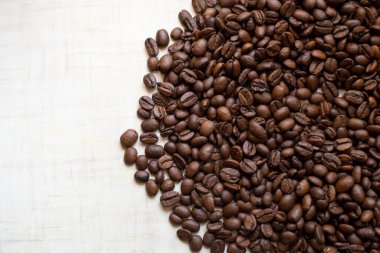 Koyu kahve taneleri açık ahşap masanın üzerinde duruyor, arka plan görüntüsü. metin için yer