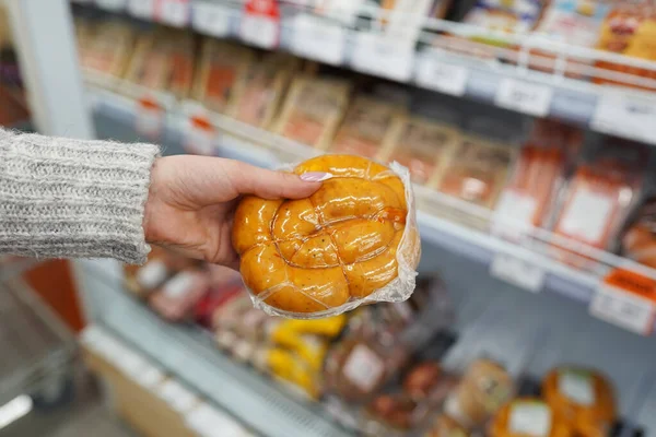 female hand holding sausages in market