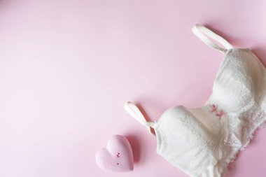 Zarif beyaz sütyen, pembe arka planda pembe kaplıca kalbi olan kadın iç çamaşırı. Uzayı kopyala Güzellik, moda blogcusu kavramı. Sevgililer Günü için romantik iç çamaşırları. hediye konsepti.