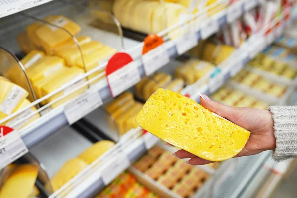 Рука покупателя с кусочком сыра в магазине — стоковое фото