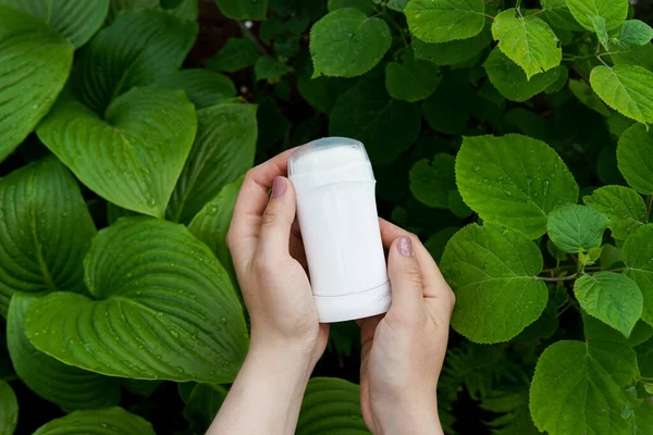 Elleri doğal terleme önleyici, deodorantı doğa yeşil arka planda.