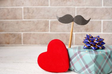 Kağıt kaplı hediye kutusu, bıyıklı, ahşap arka planda kırmızı kalp, üst manzara, Babalar Günü konsepti.