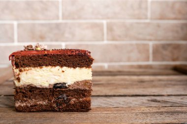 Tuğla duvarın yanındaki ahşap masada nefis çikolatalı pasta, kopyalama alanı.