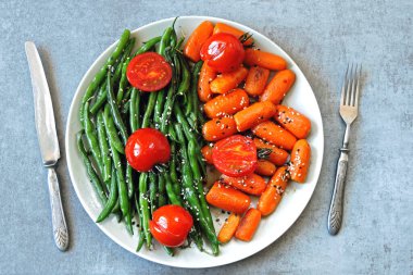 Tabakta sağlıklı yemek. Yeşil çalı fasulyesi ve ızgarada pişmiş bebek havuçları. Vejetaryen yemeği. Faydalı yeşil fasulye ve havuç salatası. Yeşil fasulye ve havuç..
