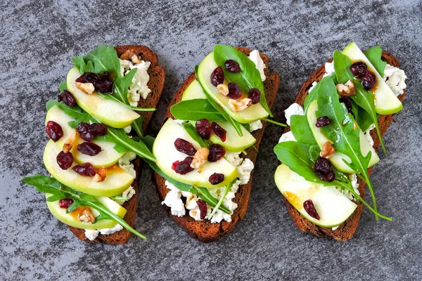 Healthy toasts with curd cheese, arugula, apple and dried cranberries. A useful snack with cottage cheese. Open sandwiches with cottage cheese, arugula and apple.