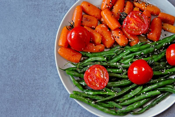 Healthy food on a plate. Green string beans and baby carrots, cooked on the grill. Vegan lunch. Useful salad of green beans and carrots. Green beans and carrots.