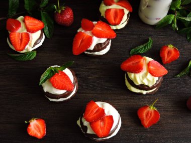 Krem peynirli ve çilekli çikolatalı kurabiyeler. Şişede çilekli süt. Üst Manzara. Süs için nane yaprakları. Olgun çilek..