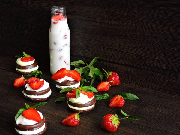 Chocolate cookies with cream cheese and strawberries. Strawberry milk drink in a bottle. Top view. Mint leaves for decoration.Ripe strawberry.