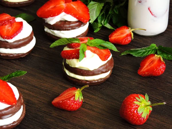 Chocolate cookies with cream cheese and strawberries. Strawberry milk drink in a bottle. Top view. Mint leaves for decoration.Ripe strawberry.