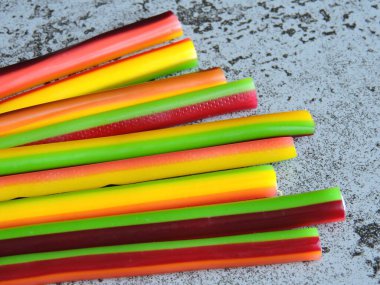 Colored fruit candy sticks. Candy-colored pencils. Copy space. clipart