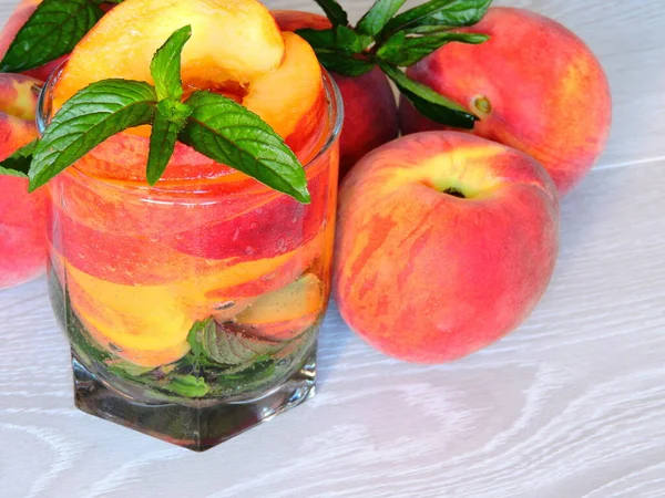 Detox drink with mint and peach. Light wooden background. Copy space.