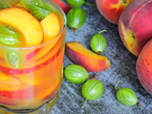 Detox drink with peach slices. Beverage for weight reduction. Pieces of peach. Tight gooseberries.