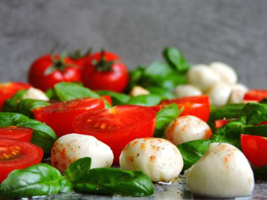 İtalyan Caprese salatası. Güneşli Caprese Salatası. Düz bir tahtada taze Caprese salatası. Fesleğen ve kiraz domateslerinin sulu yaprakları. Mozzarella topları. Biber karışımı..