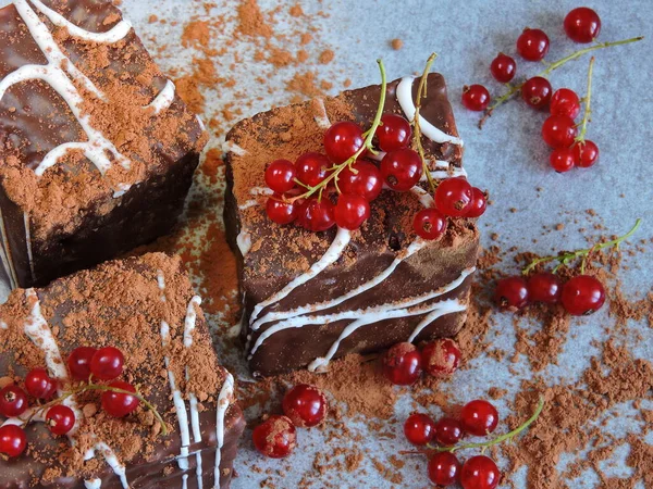 Chocolate cakes in chocolate powder with red currants. A beautiful and tasty chocolate dessert with red berries.