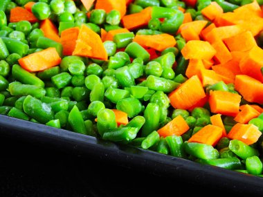Pişirmek için tavada pişirmeden önce dilimlenmiş sebzeler. Havuç, taze bezelye, taze fasulye. Sağlıklı beslenme kavramı.