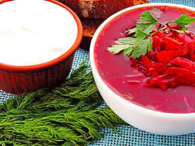 Sebzeli vejetaryen kırmızı çorba. Ekşi krema ve yeşillik. Beyaz bir kasede parlak kırmızı borç..