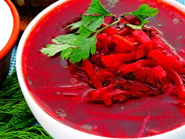 Sebzeli vejetaryen kırmızı çorba. Ekşi krema ve yeşillik. Beyaz bir kasede parlak kırmızı borç..