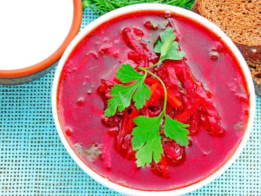 Sebzeli vejetaryen kırmızı çorba. Ekşi krema ve yeşillik. Beyaz bir kasede parlak kırmızı borç..