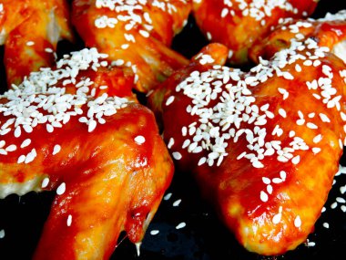 Çin usulü tavuk kanatları ve kızartma tavasında susam tohumları. Baharatlı barbekü kanatları. Baharatlı soslu susam tohumlu fırında tavuk kanadı..