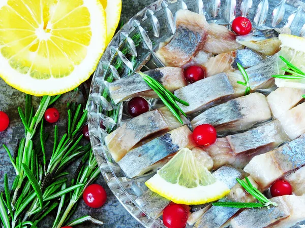 Pieces of herring in a crystal dish. Cranberry, lemon and rosemary. Norwegian herring.
