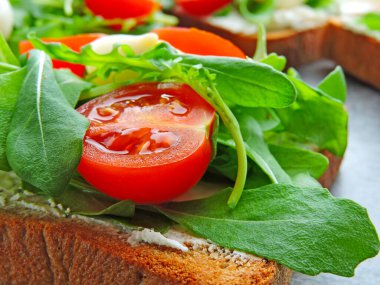 Buğday ekmekli tost roka, bıldırcın yumurtası ve vişneli domates. Faydalı atıştırmalık konsepti. Atıştırmalık bir şeyler. Parlak, lezzetli ve sağlıklı sağlık kadehleri. Roka ve krem peynirli sandviç.