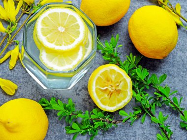 Limon suyu ve detoks suyu. Limonlu. Dallarda sarı çiçekler var. Limonlu su. Vücudu limonlu suyla temizleme fikri..