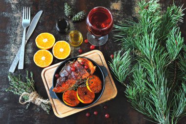 Mandalina, kekik ve kızılcıkla pişirilmiş tavuk fileto. Dökme demir tavada Noel yemeği. Noel ağacı dalları.