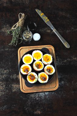 Yumuşak kaynamış yumurtalar dökme demir tavada yarıya iniyor. Bitki ve susamlı haşlanmış yumurta. Keto kahvaltısı ya da atıştırmalık. Düz yatıyordu.