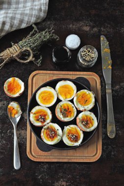 Yumuşak kaynamış yumurtalar dökme demir tavada yarıya iniyor. Bitki ve susamlı haşlanmış yumurta. Keto kahvaltısı ya da atıştırmalık. Düz yatıyordu.