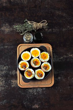 Yumuşak kaynamış yumurtalar dökme demir tavada yarıya iniyor. Bitki ve susamlı haşlanmış yumurta. Keto kahvaltısı ya da atıştırmalık. Düz yatıyordu.