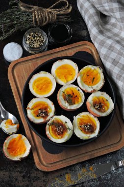 Yumuşak kaynamış yumurtalar dökme demir tavada yarıya iniyor. Bitki ve susamlı haşlanmış yumurta. Keto kahvaltısı ya da atıştırmalık. Düz yatıyordu.