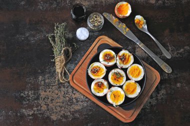 Yumuşak kaynamış yumurtalar dökme demir tavada yarıya iniyor. Bitki ve susamlı haşlanmış yumurta. Keto kahvaltısı ya da atıştırmalık. Düz yatıyordu.