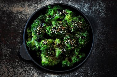 Brokoli dökme demir tavada pişmiş. Sağlıklı Çin yemeği. Vejetaryen yemeği. Yemek çubukları. Sos ve susam tohumlu fırında brokoli servis et..