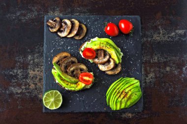 Mantarlı ve kiraz domatesli sağlıklı avokado tostları. Keto diyeti. Lezzetli malzemelerle kaplanmış avokado tostu..