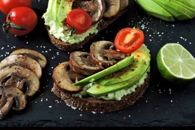 Mantarlı ve kiraz domatesli sağlıklı avokado tostları. Keto diyeti. Lezzetli malzemelerle kaplanmış avokado tostu..