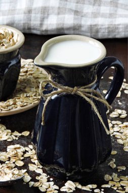 Yulaf ezmesinin arka planında süt testisindeki yulaf sütü. Vejetaryen sütü. Çevre yiyecekleri.