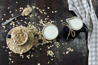 Yulaf ezmesinin arka planında süt testisindeki yulaf sütü. Vejetaryen sütü. Çevre yiyecekleri.