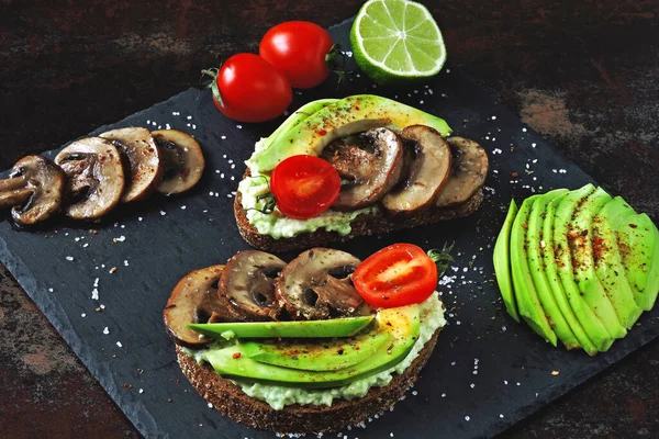 Healthy avocado toasts with mushrooms and cherry tomatoes. Keto diet. Beautifully plated avocado toast with delicious-looking toppings.