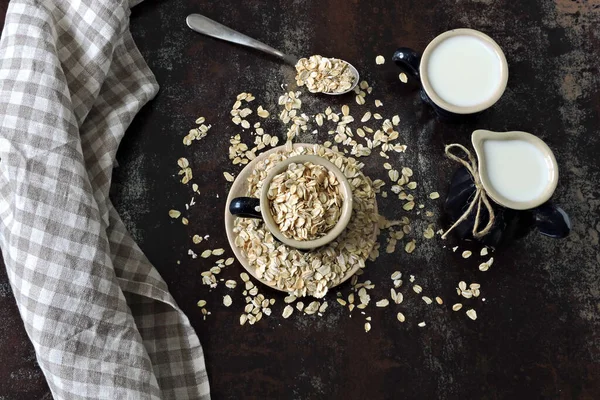 Oat milk in a milk jug on the background of oatmeal. Vegan milk. Eco food.