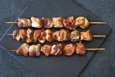 Karanlık bir taş yüzeyde iştah açıcı kebaplar. Üst görünüm.