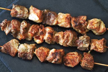 Karanlık bir taş yüzeyde iştah açıcı kebaplar. Üst görünüm.