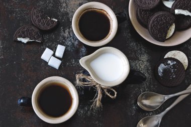 İki fincan kahve, çikolatalı süt kurabiyesi ve sütlü sürahi. Kötü bir stil. Sabah kahvesi konsepti.