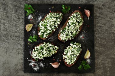 Taş bir tahtanın üzerinde kremalı sandviç. Süzme peynirli, yeşillikli ve sarımsaklı sandviç. Keto diyeti. Doğru atıştırmalık konsepti.