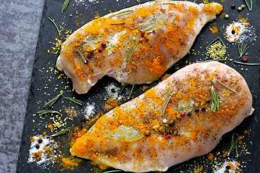 Çiğ tavuklu fileto, zerdeçal ve baharatlı taş bir tahtada marine edilmiş. Üst Manzara. Köri pişiriyorum..