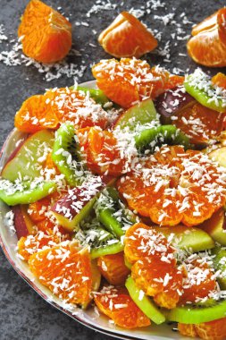 Mandarin, kivi, elma ve hindistan cevizi taneli parlak meyve salatası. Vejetaryen meyve salatası. Yararlı bir tatlı konsepti. Tropik salata. Detoks gıdası.