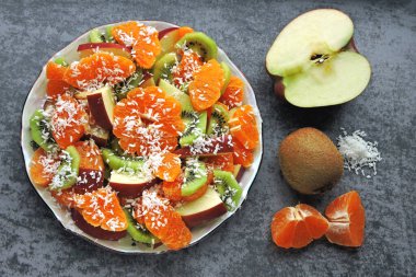 Mandarin, kivi, elma ve hindistan cevizi taneli parlak meyve salatası. Vejetaryen meyve salatası. Yararlı bir tatlı konsepti. Tropik salata. Detoks gıdası.