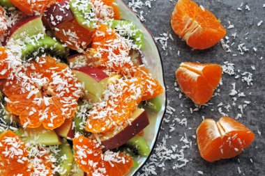 Mandarin, kivi, elma ve hindistan cevizi taneli parlak meyve salatası. Vejetaryen meyve salatası. Yararlı bir tatlı konsepti. Tropik salata. Detoks gıdası.