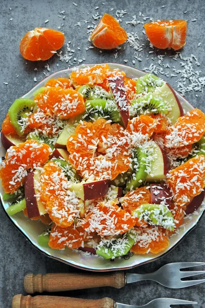 Bright fruit salad with mandarin, kiwi, apple and coconut flakes. Vegan fruit salad. The concept of a useful dessert. Tropical Salad. Detox food.